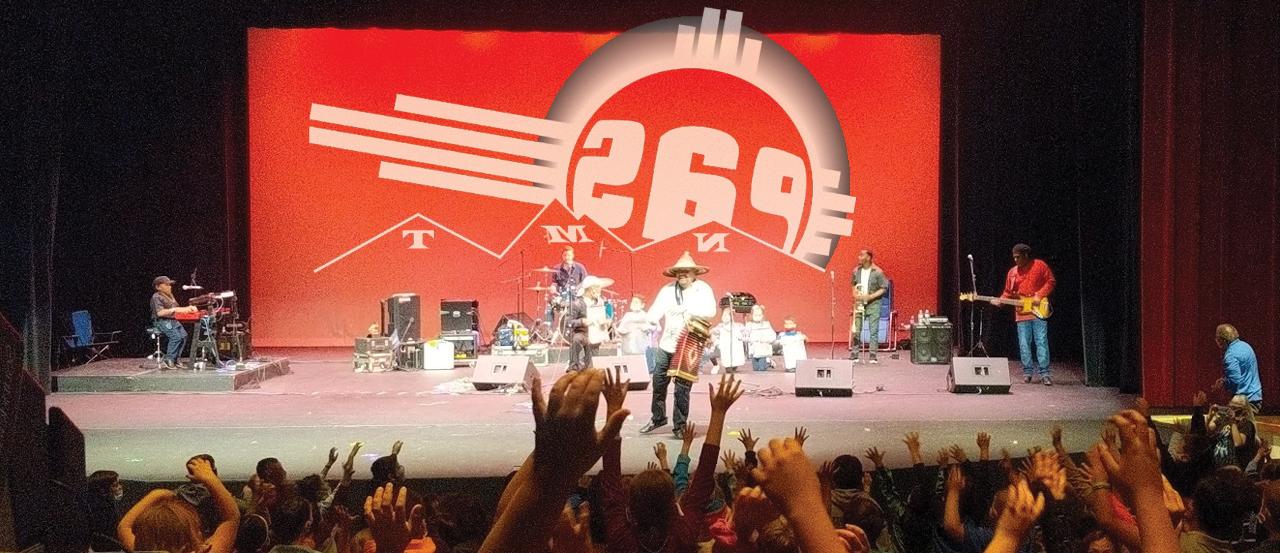 A picture from the crowd's view of a performance on the stage. The Performing Arts Series logo is prominent on the image.